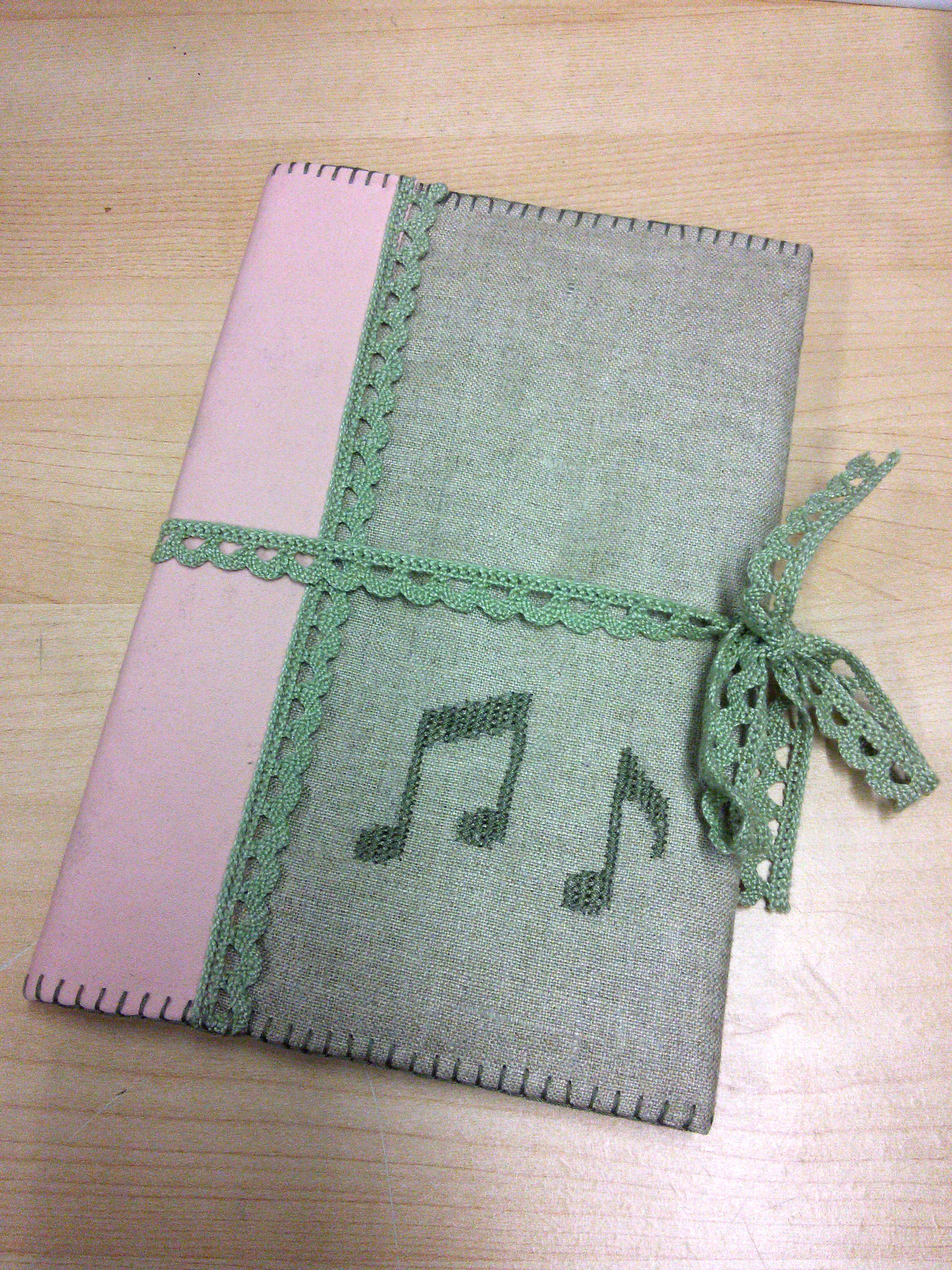 A photo of my songbook's cover, closed with a lacy ribbon tied around it.