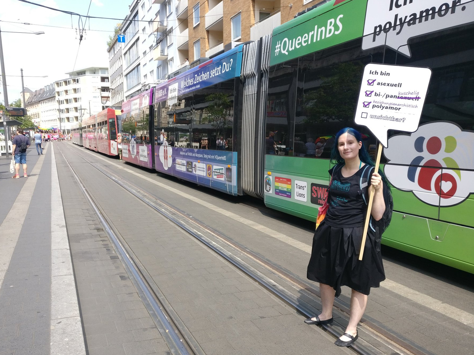 photo of me standing in front of the rainbow tram with my sign